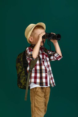 Sırt çantalı küçük turist dürbünle bakıyor..