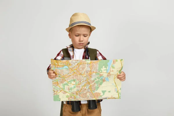 Liten pojke turist med ryggsäck innehav kikare och karta. — Stockfoto