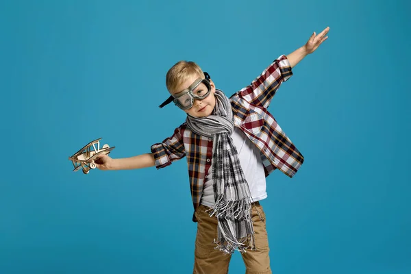 Barn pojke i retro glasögon leka med trä leksak flygplan — Stockfoto