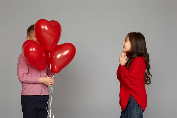 Pareja de niña y niño con globos de corazón rojo —  Fotos de Stock