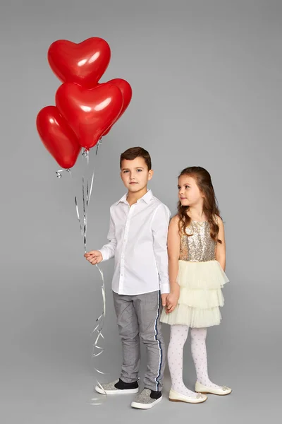 Pareja de niña y niño con globos de corazón rojo — Foto de Stock