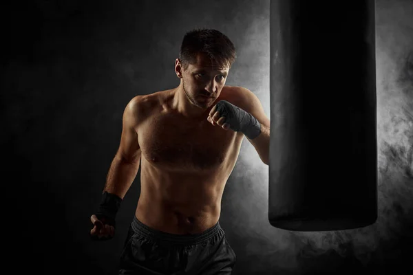 Masculino boxer perfuração no boxe saco no preto fundo — Fotografia de Stock
