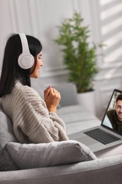 Dizüstü bilgisayar kullanan kulaklıklı güzel bir kadın.