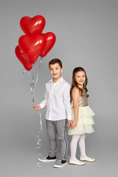 Pareja de niña y niño con globos de corazón rojo — Foto de Stock