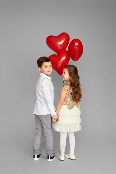 Pareja de niña y niño con globos de corazón rojo — Foto de Stock