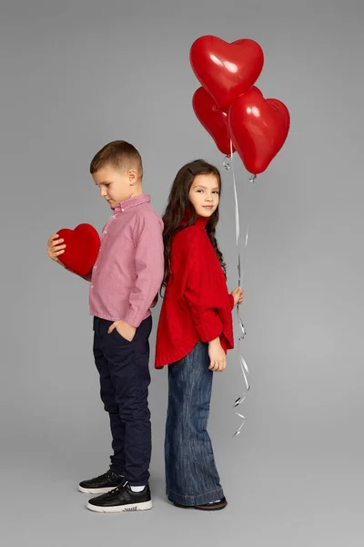 Pareja de niña y niño con globos de corazón rojo — Foto de Stock