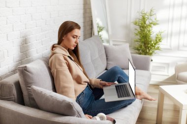 Evde dizüstü bilgisayar kullanan genç bir kadın.