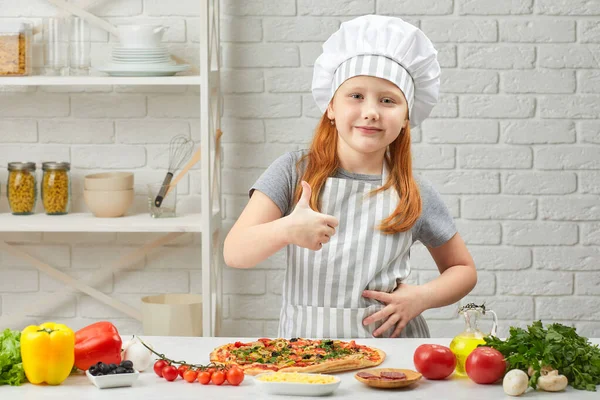 Kislány séf kalapban és kötény főzés pizza — Stock Fotó