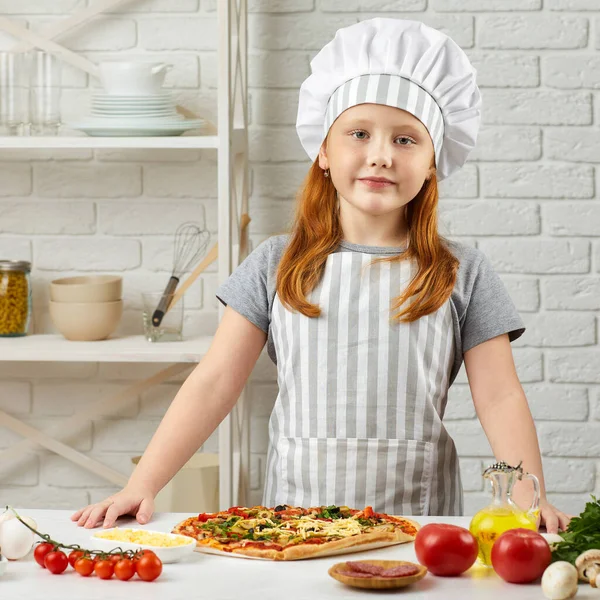 Kislány séf kalapban és kötény főzés pizza — Stock Fotó