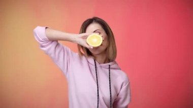 Portakal tutan ve dans eden pembe elbiseli bir kadın.