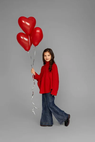 Mutlu kız elinde kırmızı kalp şeklinde balon tutuyor. — Stok fotoğraf