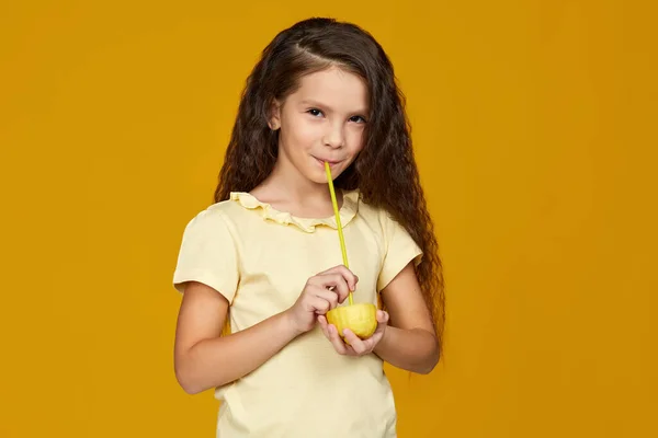 Мила маленька дівчинка тримає свіжий лимон і п'є сік — стокове фото