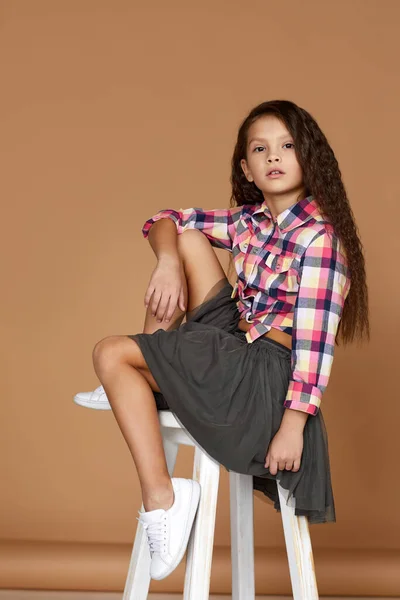 Lockigt litet barn flicka sitter på stol — Stockfoto