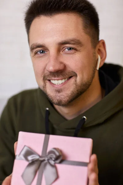 Man in earphones holding a gift box — Stock Photo, Image