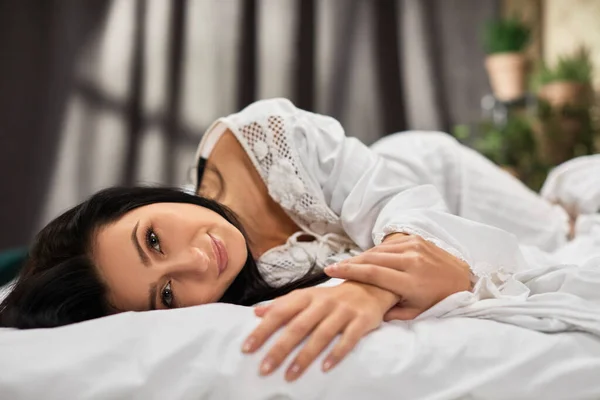 Woman with long hair is sitting on the bed — Stock Photo, Image