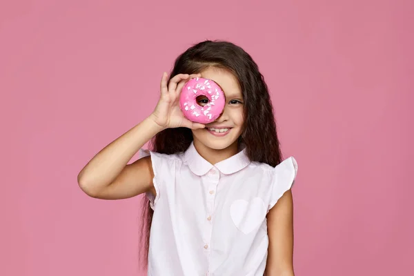 Усміхнена дівчинка тримає смачний пончик — стокове фото