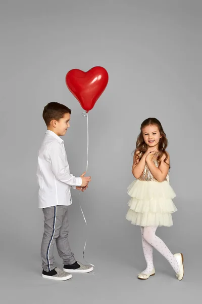 Pareja de niña y niño con globos de corazón rojo — Foto de Stock