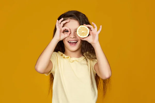 Мила маленька дівчинка тримає свіжий соковитий лимон — стокове фото