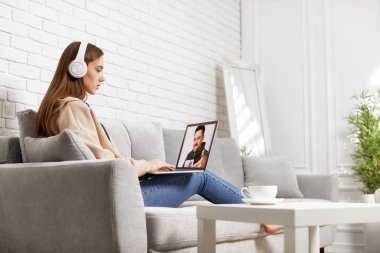 Evde dizüstü bilgisayar kullanan genç bir kadın.