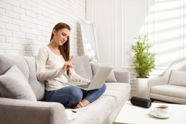 Evde dizüstü bilgisayar kullanan genç bir kadın.