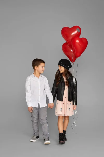 Pareja de niña y niño con globos de corazón rojo — Foto de Stock