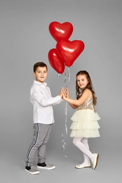 Pareja de niña y niño con globos de corazón rojo — Foto de Stock