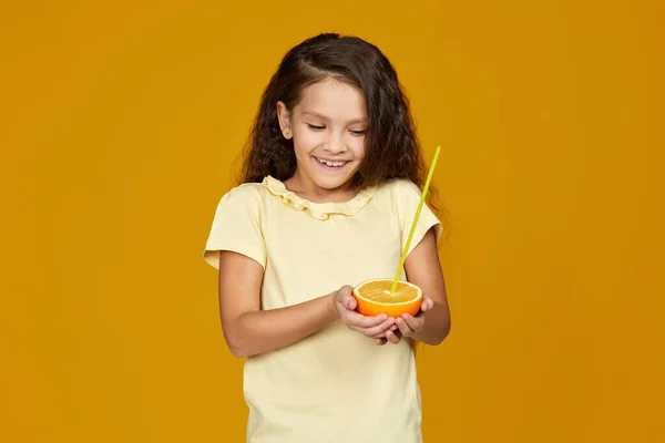 Дитяча дівчина тримає свіжий соковитий грейпфрут і п'є сік — стокове фото