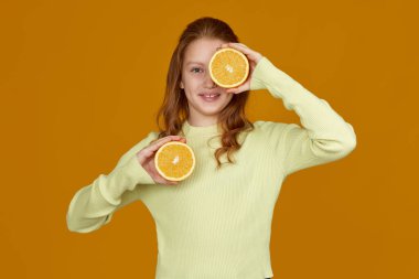 Çocuk elinde taze portakal tutuyor.