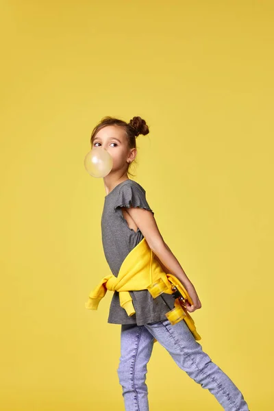 Menina com skate soprando uma pastilha elástica grande — Fotografia de Stock