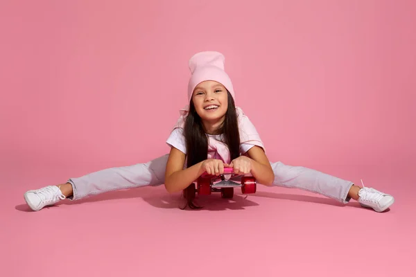 Niña riendo y sentada en patineta rosa — Foto de Stock