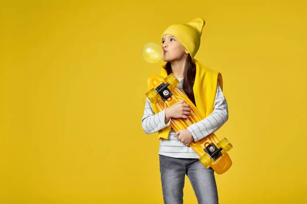 Дитяча дівчина зі скейтбордом дме велику жувальну гумку — стокове фото