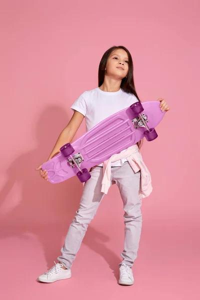 Маленька дівчинка тримає рожевий скейтборд — стокове фото