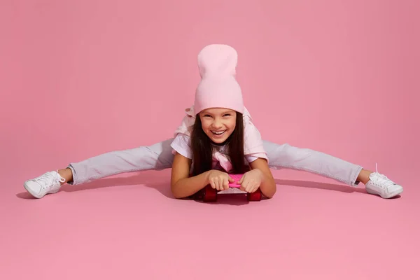 Kind meisje lachen en zitten op roze skateboard — Stockfoto