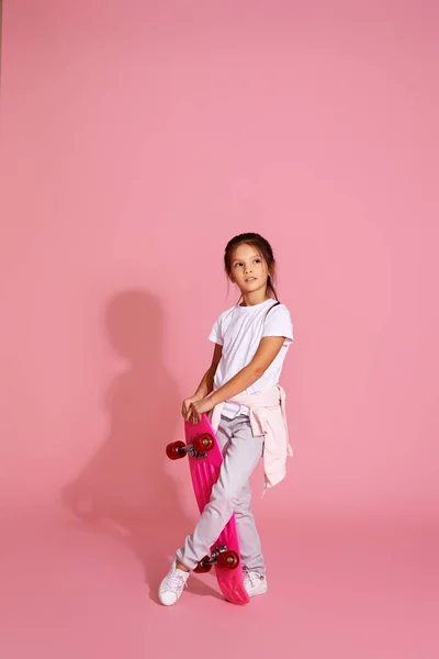 Маленька дівчинка тримає рожевий скейтборд — стокове фото