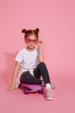 Kaykayda oturan tatlı küçük kız.