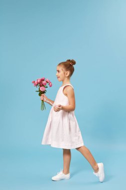 Sevimli, gülümseyen küçük kız elinde bir buket gül tutuyor.