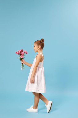 Sevimli, gülümseyen küçük kız elinde bir buket gül tutuyor.