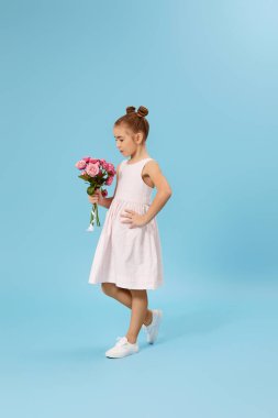 Sevimli, gülümseyen küçük kız elinde bir buket gül tutuyor.