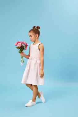 Sevimli, gülümseyen küçük kız elinde bir buket gül tutuyor.