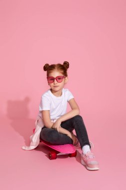 Kaykayda oturan tatlı küçük kız.