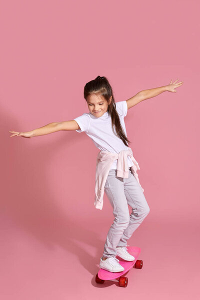 милая счастливая маленькая девочка катается на скейтборде