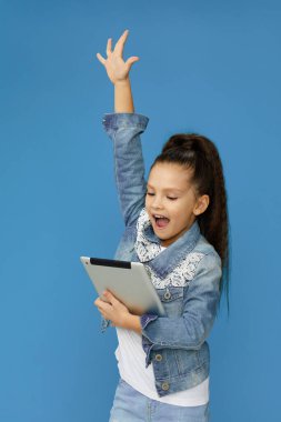 Dijital tablet kullanan kot giyen küçük kız.