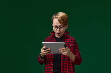 dijital tablet kullanan kırmızı kareli tişörtlü çocuk