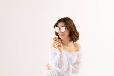 Waffle külahında vanilyalı dondurmayla beyaz elbiseli güzel bir genç kadın. yumuşak ışık. Metin için boşluk