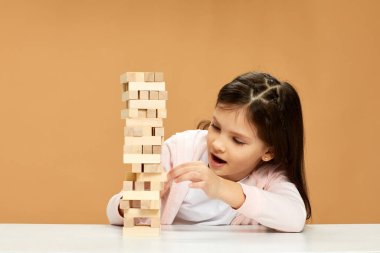 Çocuklar masa başında ahşap inşaatçıyla oynuyorlar..