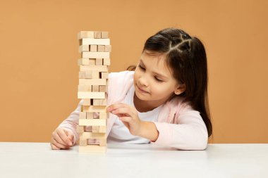 Çocuklar masa başında ahşap inşaatçıyla oynuyorlar..