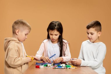 Coşkulu çocuklar stüdyoda elektronik devreler topluyor.