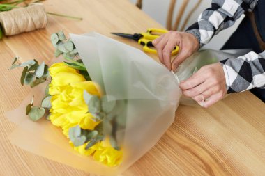 Çiçekçi taze sarı lalelerden bir buket yapar..