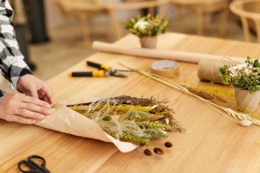 Çiçekçi kadın kurutulmuş çiçeklerden buket yapar.