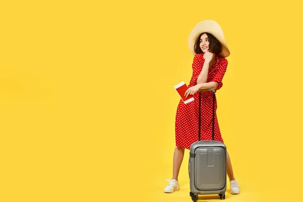 woman with suitcase going traveling on yellow background.